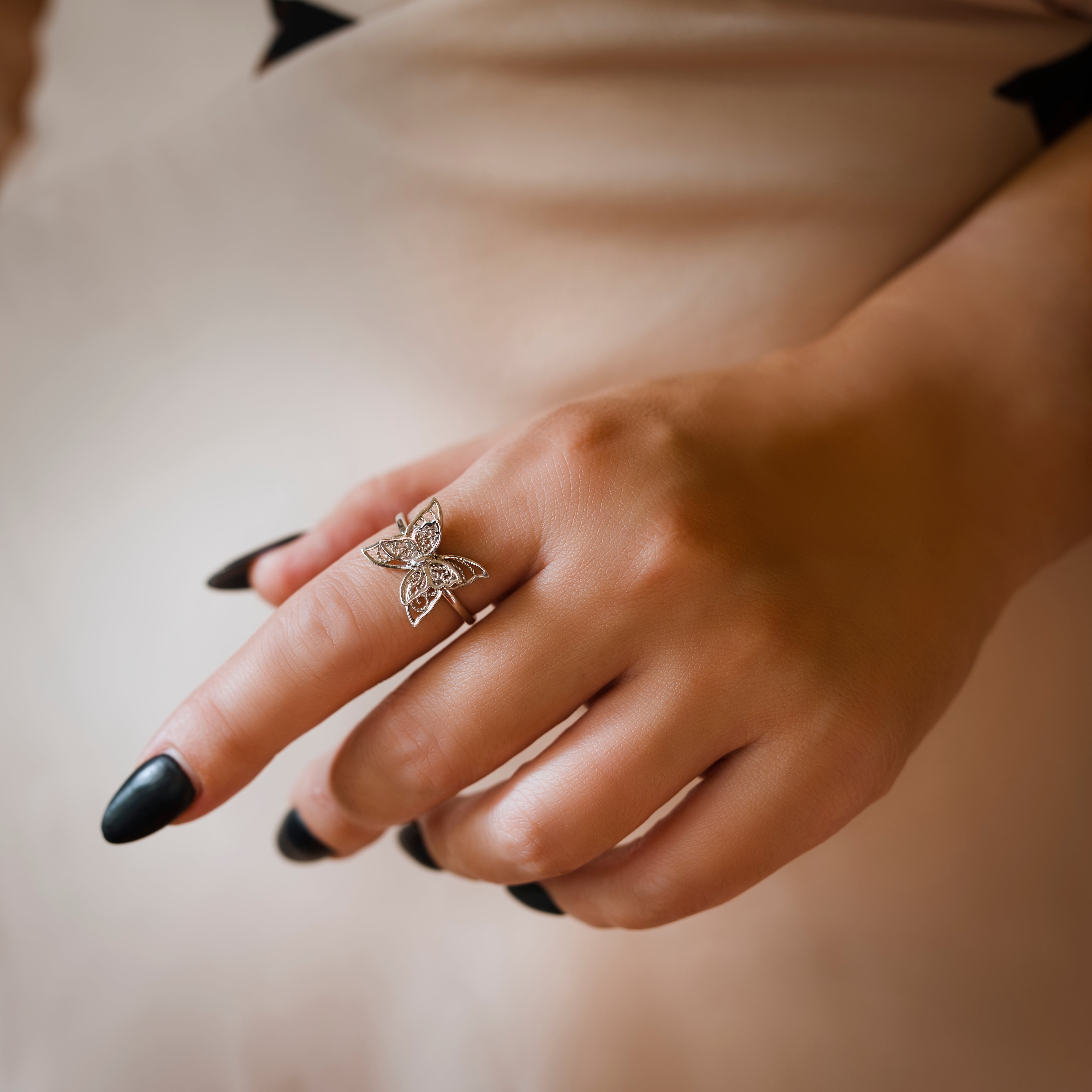 Hand wearing a butterfly-shaped ring with a blurred background